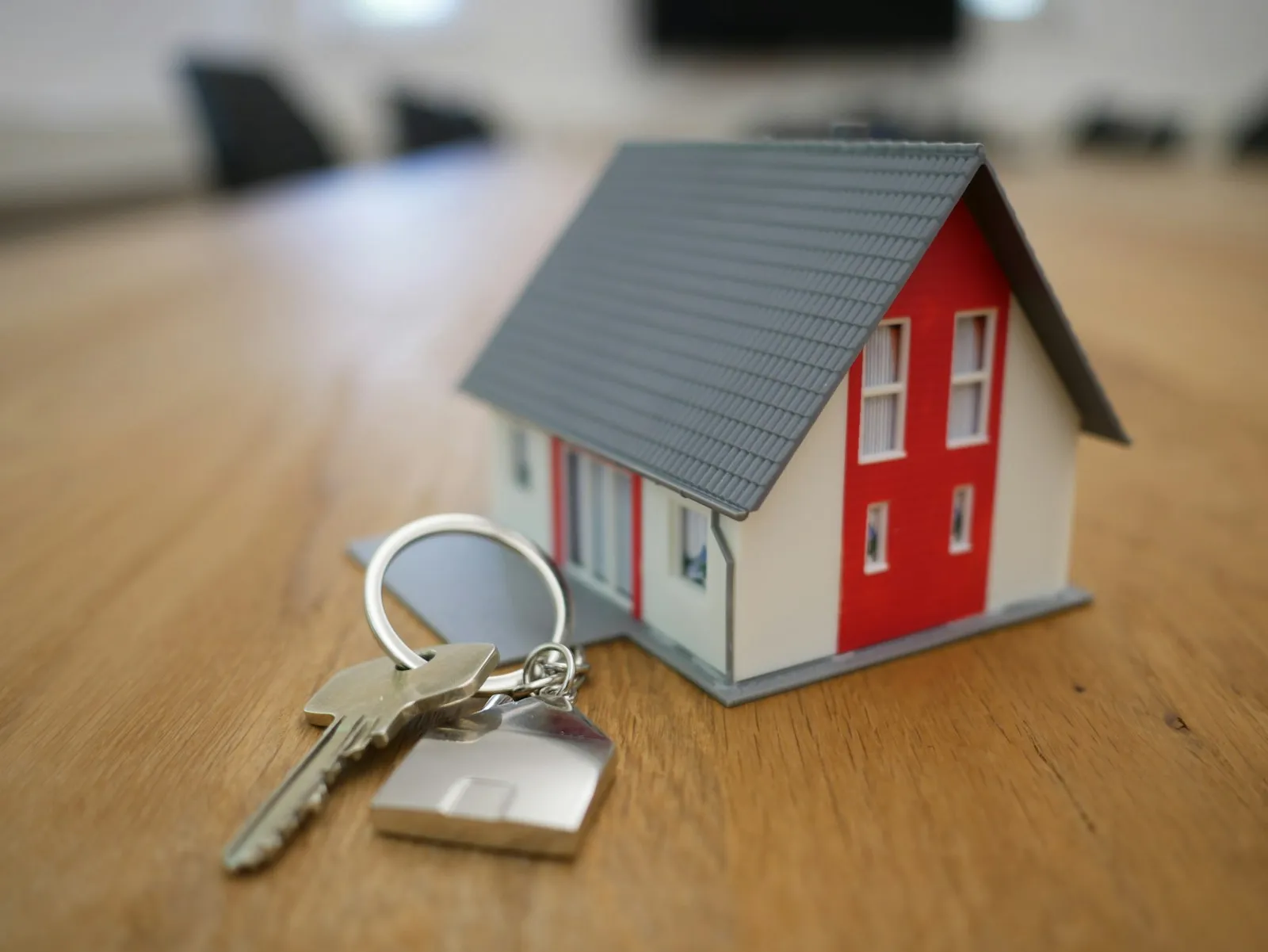 Miniatura de casa de madeira ao lado de chaves sobre mesa de contratos representando hipoteca e alienação fiduciária no crédito imobiliário brasileiro