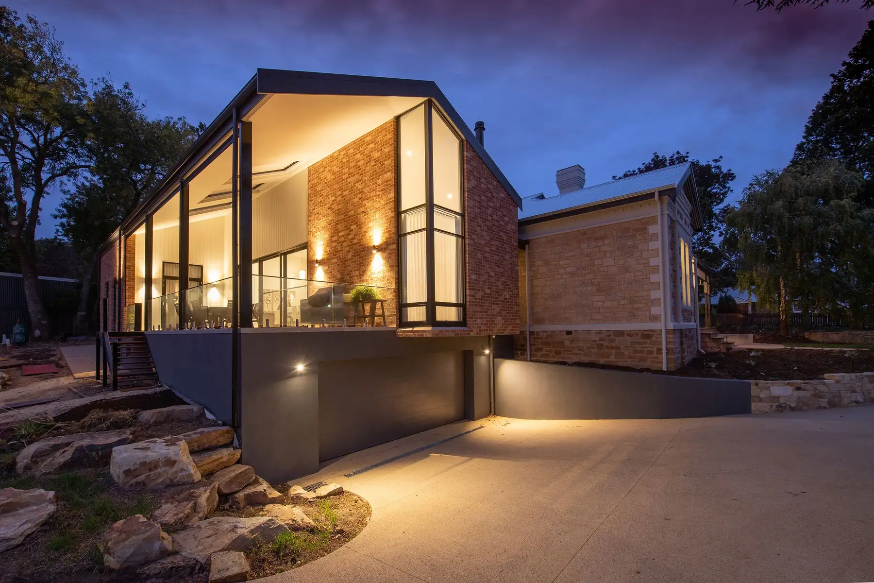 Casa contemporânea de alto padrão iluminada ao anoitecer, com fachada de tijolo e pedra e amplos vidros acesos, representando o patrimônio sólido usado como garantia no home equity