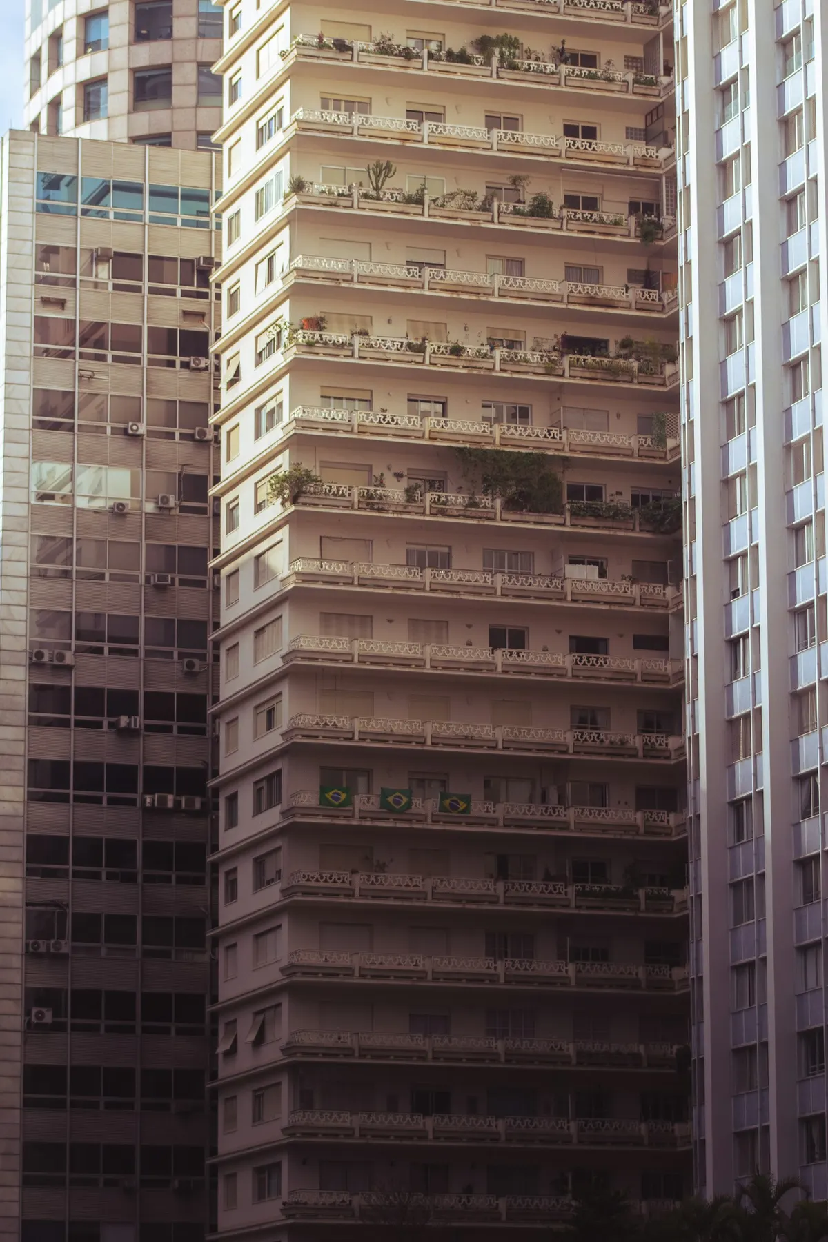 Fachadas de prédios residenciais brasileiros vistos de perto, com bandeira do Brasil em uma das varandas