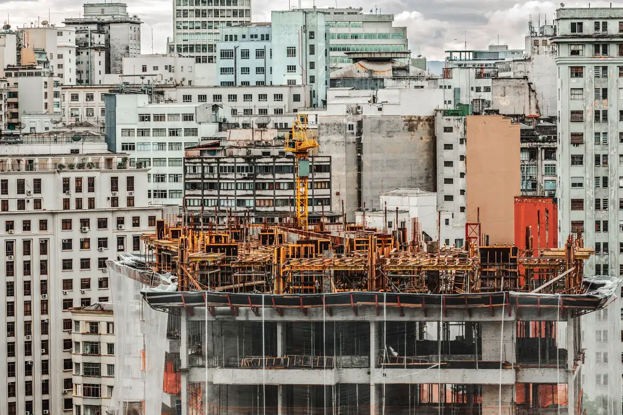 Canteiro de obras de um edifício residencial em construção, com estrutura de concreto e grua, representando a fase da obra que mais consome caixa