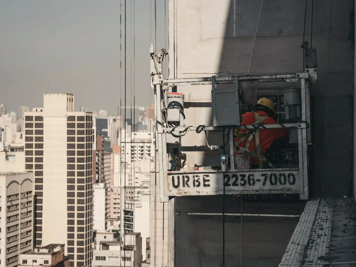 Trabalhador em balancim fazendo manutenção na fachada de um prédio em São Paulo