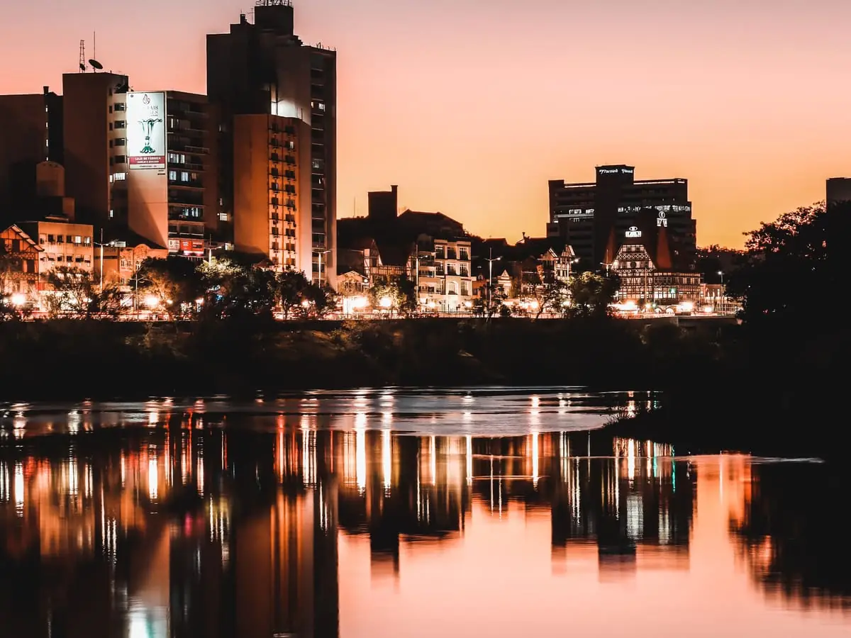 Skyline de Blumenau (SC) refletida no Rio Itajaí-Açu ao entardecer — sede da Credios